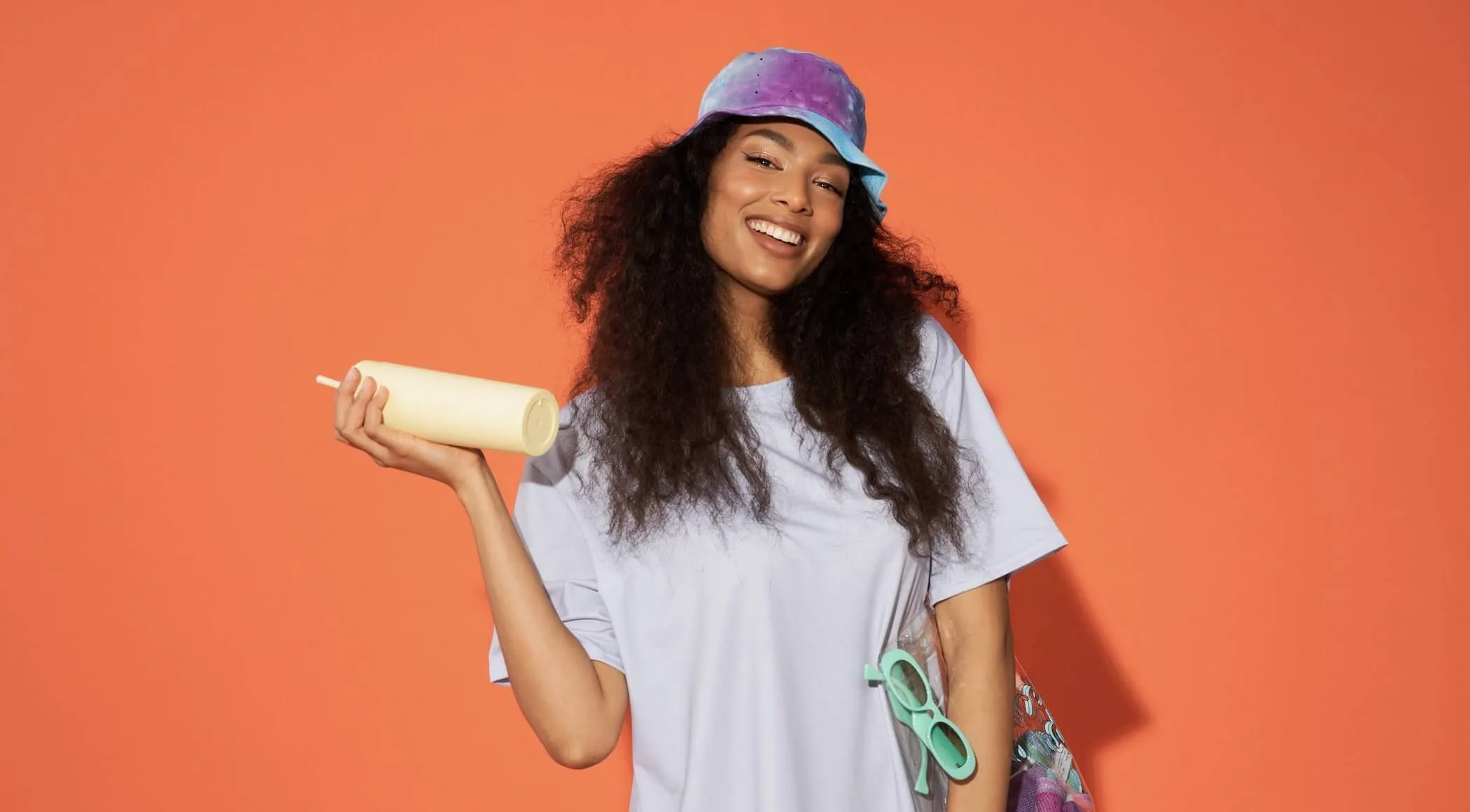 A woman holding a glass of juice, with a sunny and refreshing vibe.